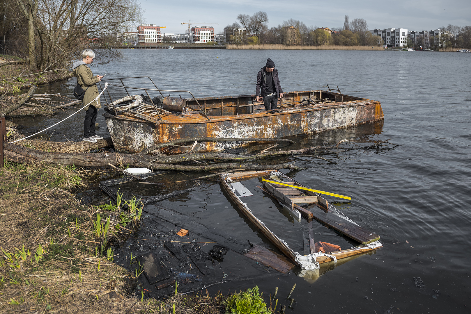 Ausgebrannte Boote von Lummerland. Mahoudi (?) begutachtet was von seinem Boot übrig geblieben ist. Rummelsburger Bucht, Berlin Lichtenberg, 25.03.2017